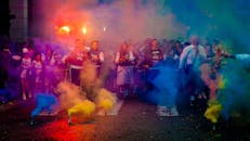 一群人在热闹的街头节日中，夜间用彩色烟雾弹庆祝