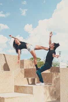 Energetic acro yoga couple practicing balance and strength in an outdoor setting.