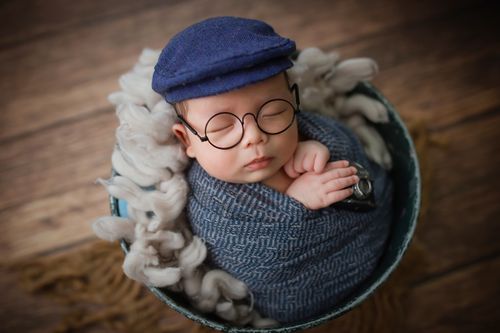 Free Charming newborn baby boy wrapped snugly, wearing a stylish cap and eyeglasses, symbolizing warmth and innocence. Stock Photo