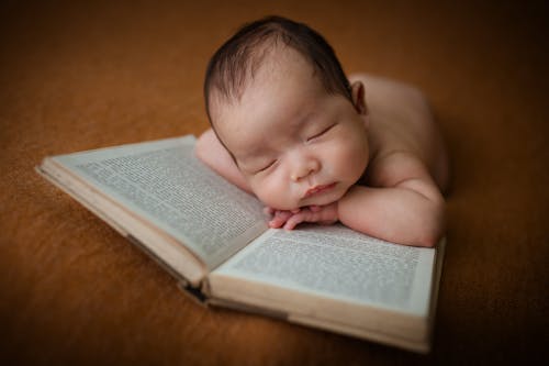 Free A Cute Baby Lying on the Book Stock Photo