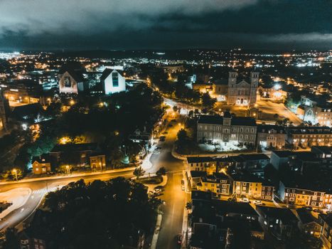 Aerial view of a city lit up at night, showcasing urban architecture and illuminated streets.