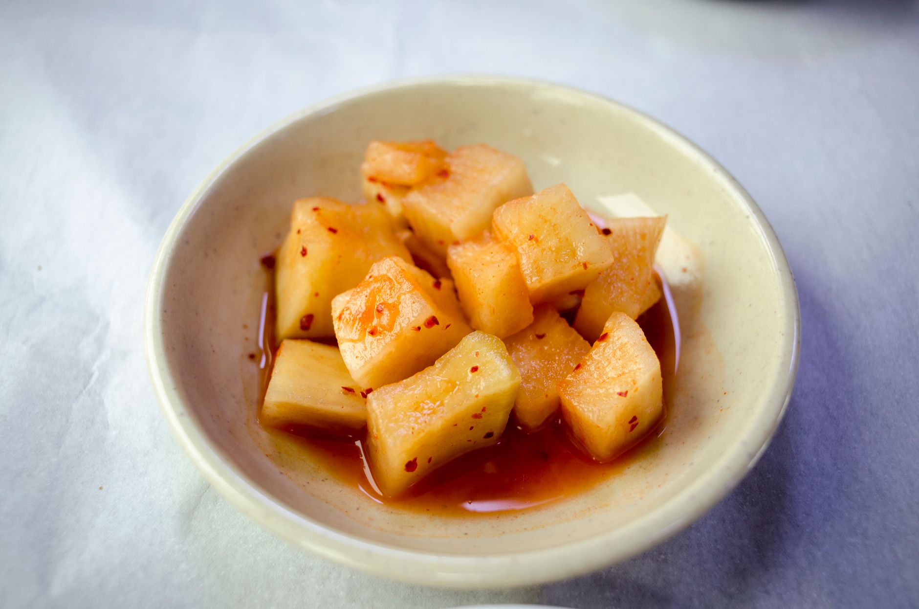 Close-up of traditional Korean radish kimchi in a bowl, highlighting its vivid colors and spicy flavors.