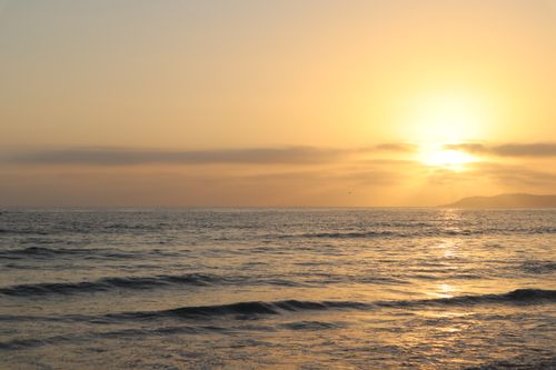 Free A tranquil ocean scene at sunset with golden reflections on the water, creating a peaceful atmosphere. Stock Photo