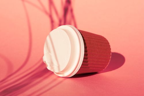 Free Aesthetic close-up of a disposable coffee cup on a vibrant pink surface with striking shadows. Stock Photo