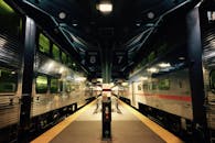 火车站夜间灯光昏暗，有两列火车停靠，展示了轨道和站台的设计