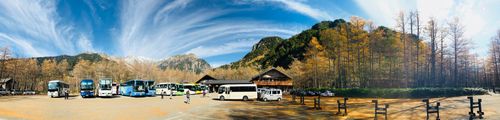 Free Panoramic view of buses parked by mountain in autumn, clear sky above. Stock Photo