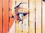 天然木栅栏上画着一幅生动的艺术壁画，描绘了一只哭泣的眼睛