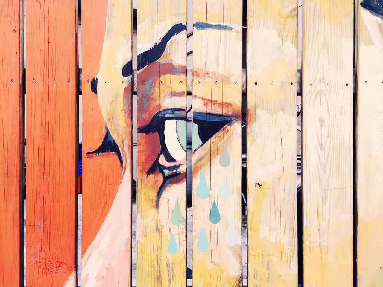 vivid artistic mural depicting a crying eye painted on a natural woode