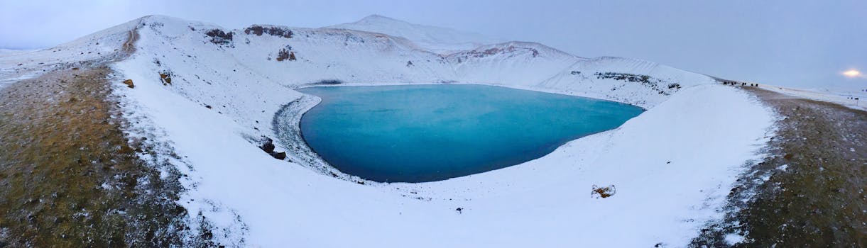 在多云的冬季天空下，宁静的冰冻湖泊映衬着迷人的雪山景观