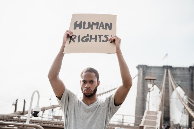 Man In A Gray Shirt Holding A Human Rights Sign