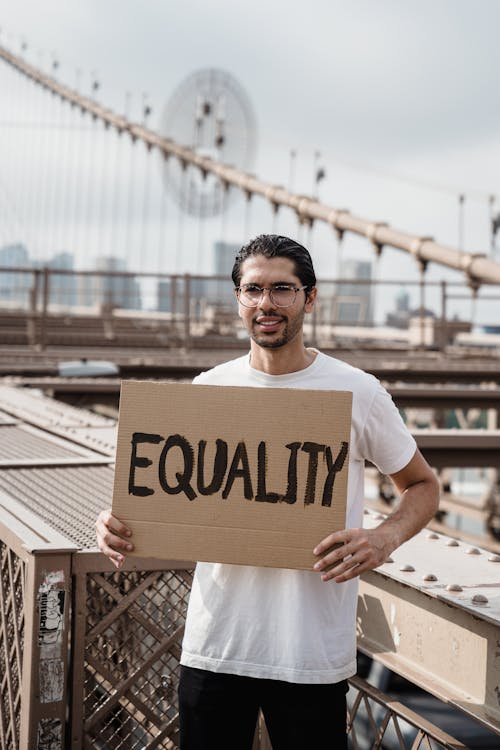 Free A Man Standing Holding a Placard on a Bridge Stock Photo