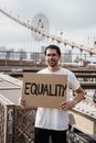 A Man Standing Holding a Placard on a Bridge