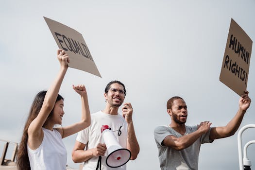 A diverse group of activists hold placards and megaphone advocating for equality and human rights.