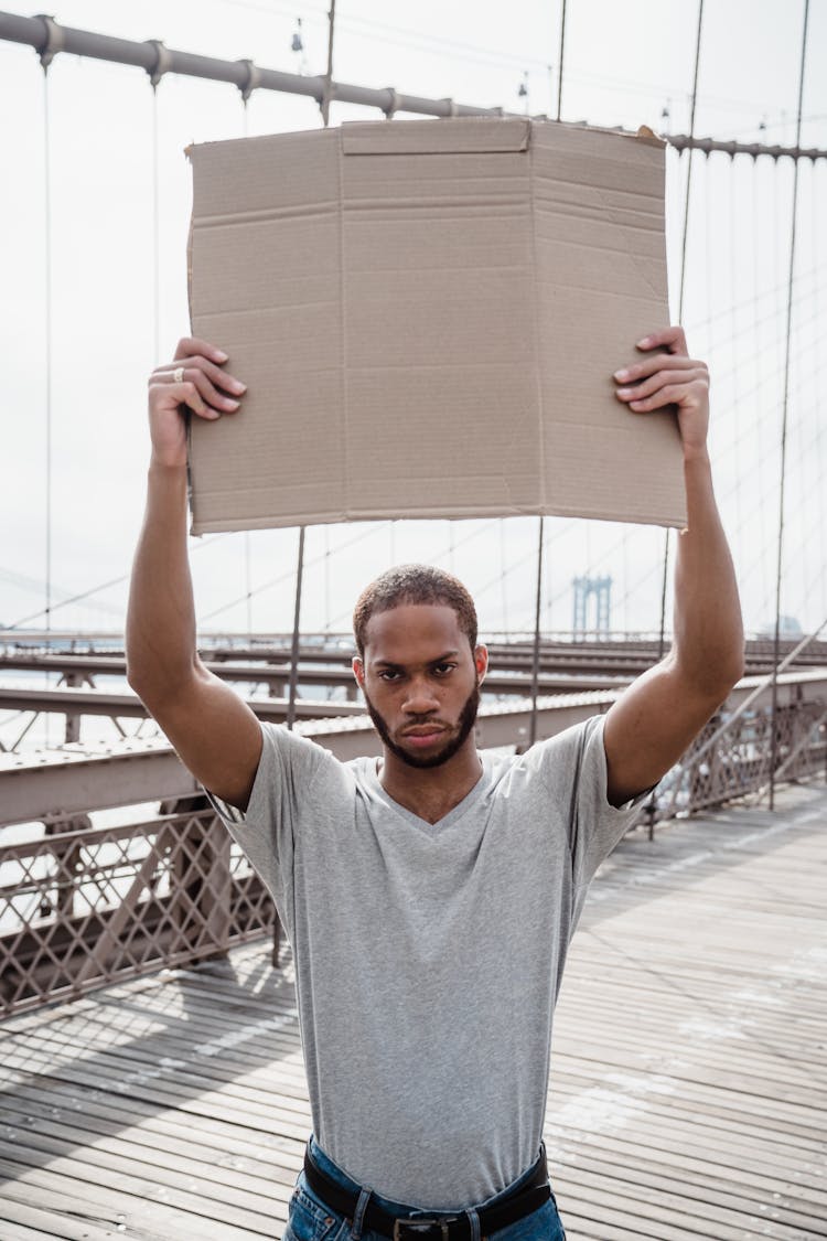 Man In Gray Shirt Holding A Blank Placard