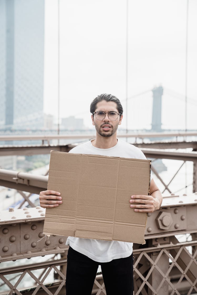 Man In White Crew Neck Shirt Holding A Blank Cardboard Placard