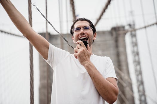 Man raising his arm while speaking through a megaphone on a bridge, expressing protest.