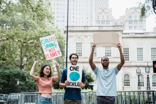 Young activists holding climate change signs in a city protest rally outdoors.