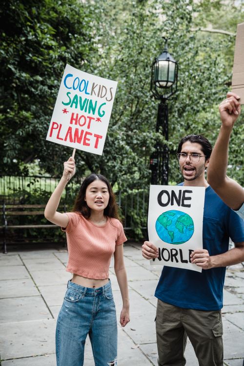 Free Young activists displaying climate change protest signs during an outdoor rally. Stock Photo