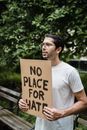 Man in White Crew Neck T-shirt Holding Brown Wooden Signage