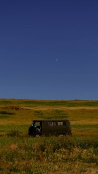 A vintage van parked in a scenic rural landscape under a clear blue sky.