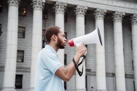 Person using a megaphone in a peaceful protest outside a court building.