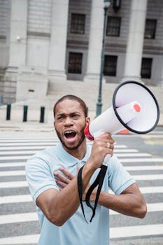 A passionate protester shouts into a megaphone on a city street, advocating nonviolence.