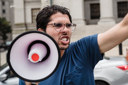 Man in Blue Crew Neck T-shirt Wearing Eyeglasses Holding a Megaphone