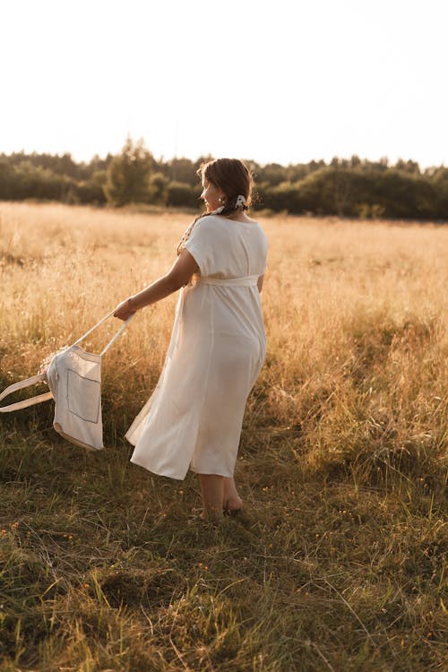 Woman Holding Her Bag on a Grass Field