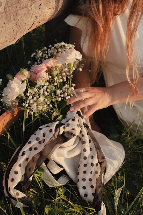 A Woman Holding a Bouquet of Roses with Baby's Breath Wrapped in Polka Dots Scarf