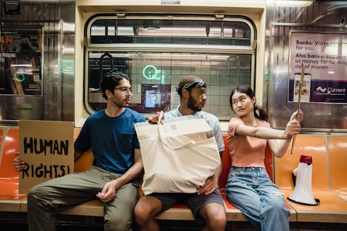 People Sitting in the Train while Holding Posters