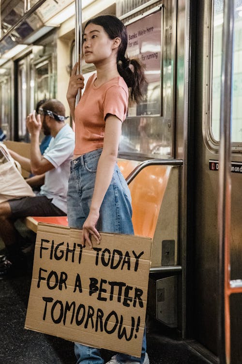 Woman riding a Train and Holding a Slogan 