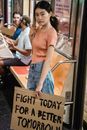 Woman riding a Train and Holding a Slogan