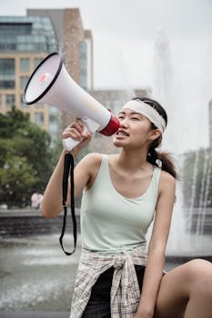 A young woman passionately protesting with a megaphone in an outdoor urban setting.