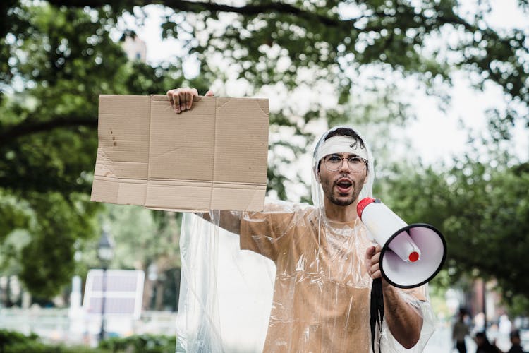 Man With A Megaphone Holding A Cardboard Sign