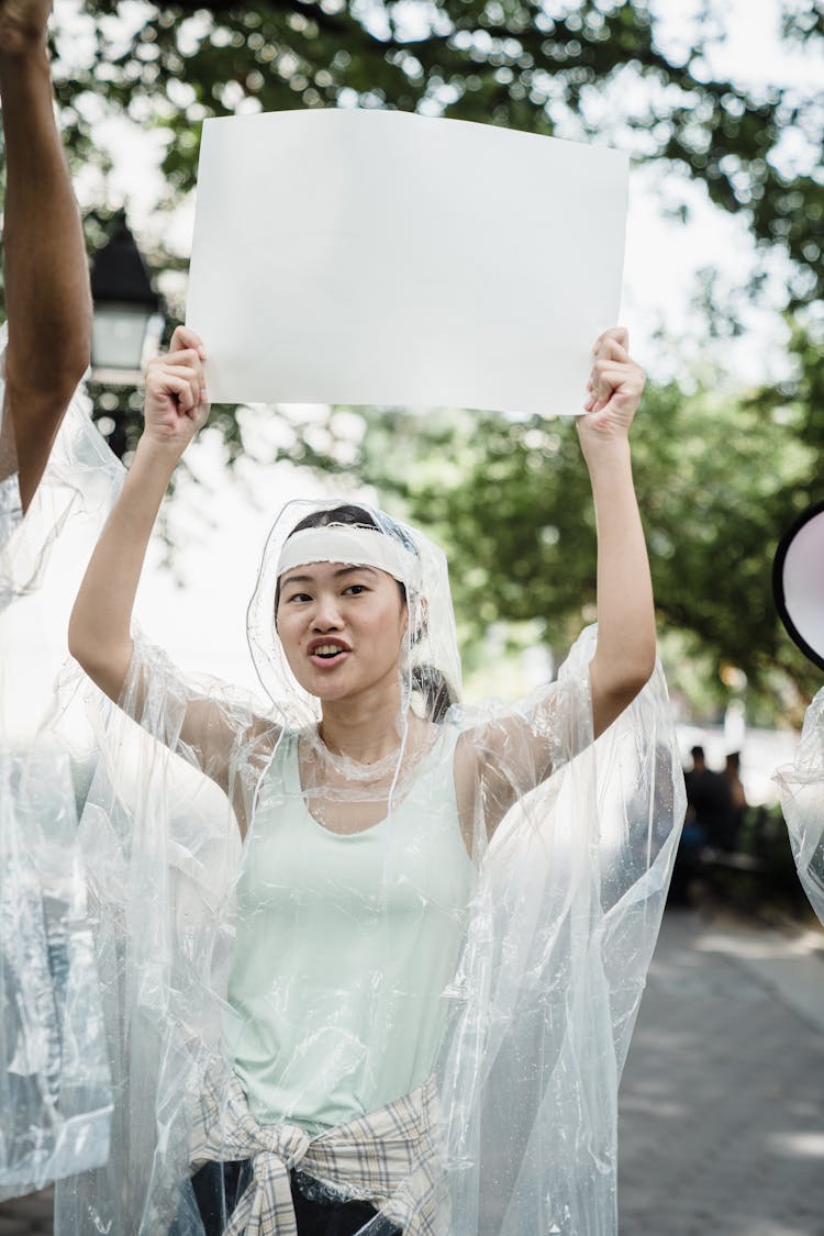 A Woman In A Transparent Raincoat Holding A Placard