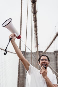 Person passionately protesting with a megaphone on the iconic Brooklyn Bridge.