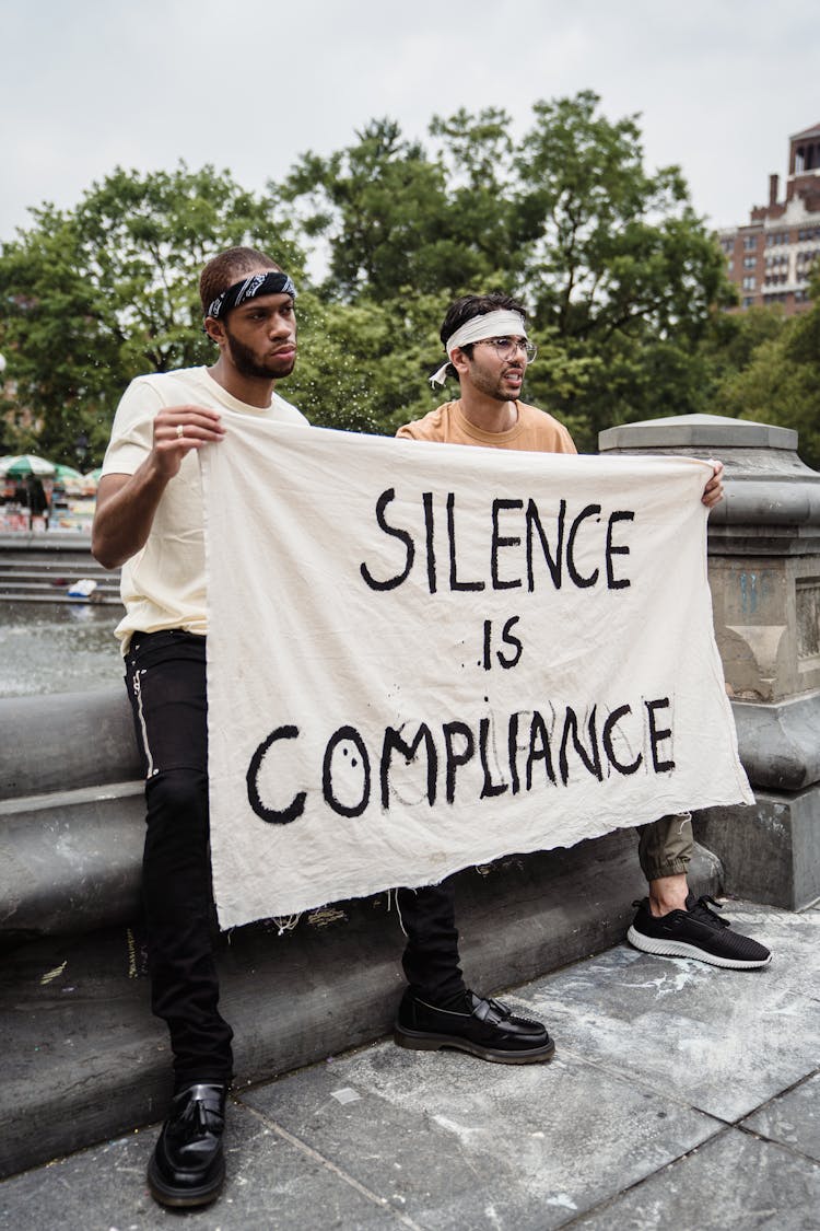 Men Standing On The Street While Holding A Banner