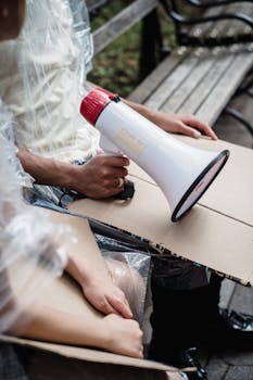 A protester sits with a megaphone and signs, ready to voice their message.