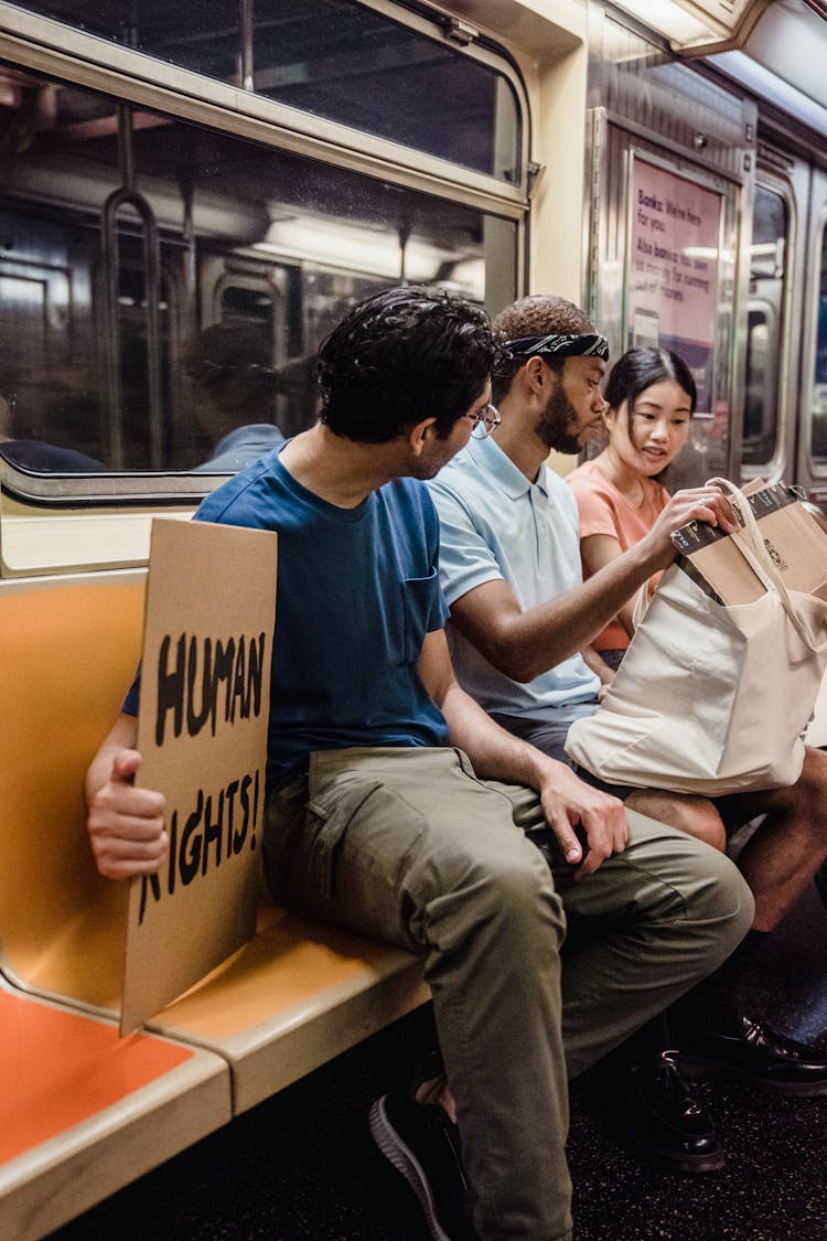 A Group Of People Sitting Inside The Train While Having Conversation