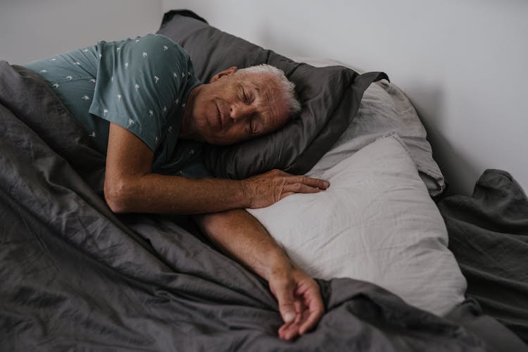 An Elderly Man Sleeping On The Bed