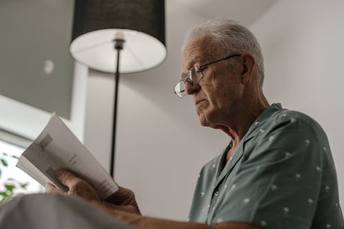 A Low Angle Shot of an Elderly Man Reading a Book