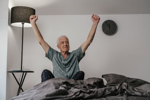 Senior man in pajamas waking up with arms stretched in a cozy bedroom setting.