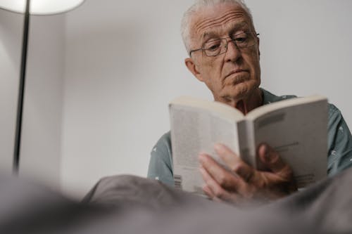 Free Close-Up Shot of an Elderly Man with Eyeglasses Reading a Book Stock Photo