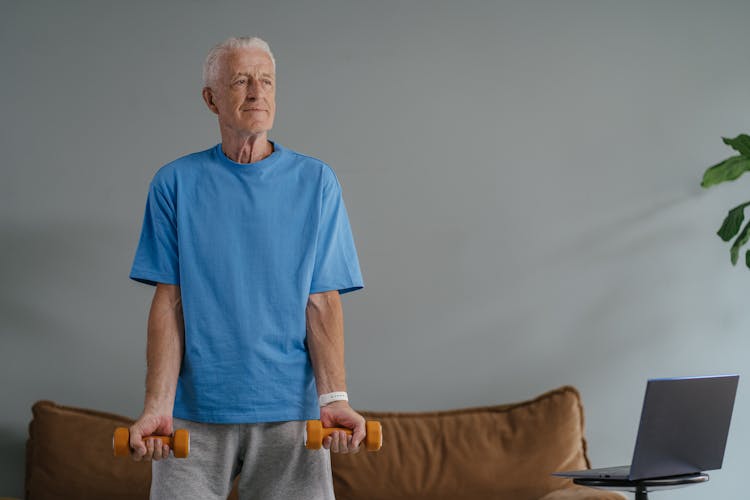 An Elderly Man In Blue Shirt Holding A Dumbbells