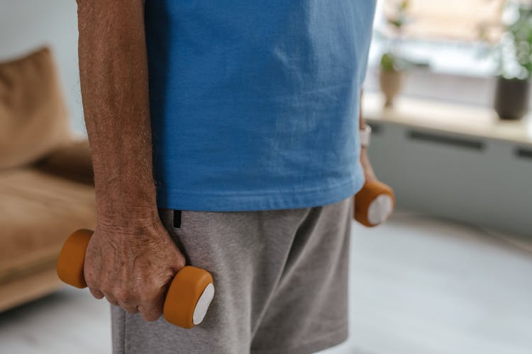 A Person In Blue Shirt Holding Dumbbells