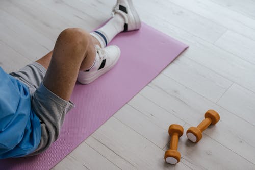 A Person Wearing Gray Shorts Sitting on the Yoga Mat