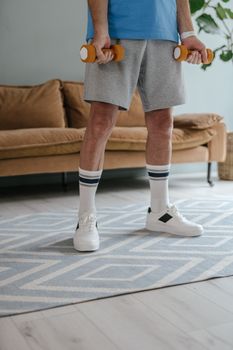 Adult male exercising with dumbbells indoors, emphasizing a healthy lifestyle.