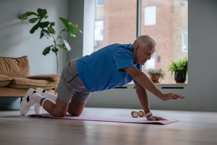 An Elderly Man Exercising On A Yoga Mat 