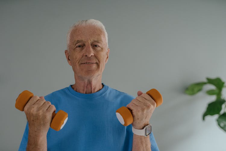 An Elderly Man In Blue Shirt Holding Dumbbells