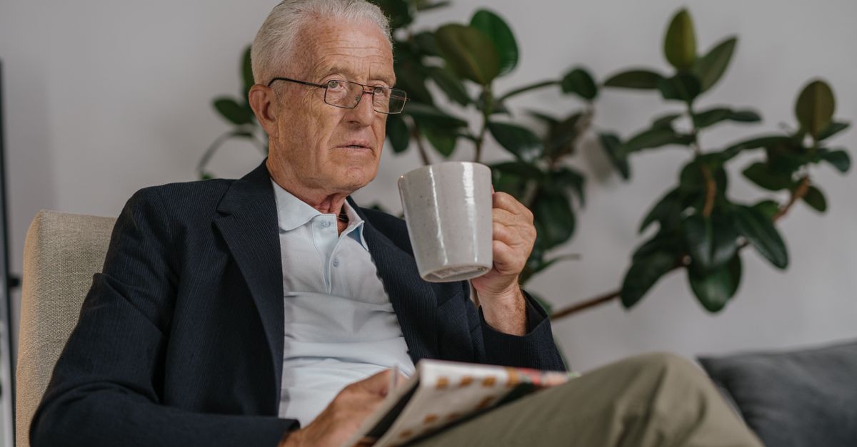 person holding a coffee mug next to a dumbbell, looking tired